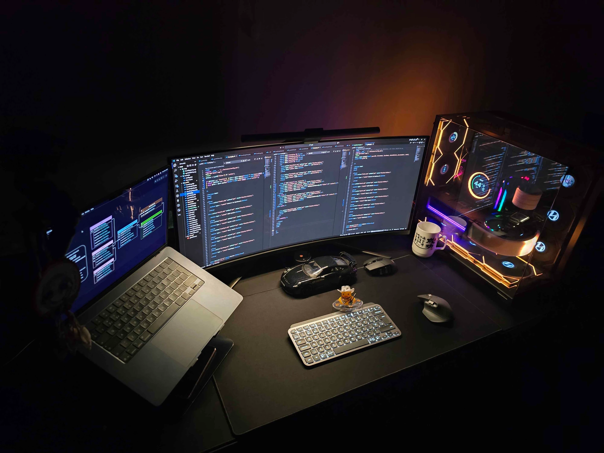 Desk setup — dual monitors running an editor and code, a PC build, and a MacBook